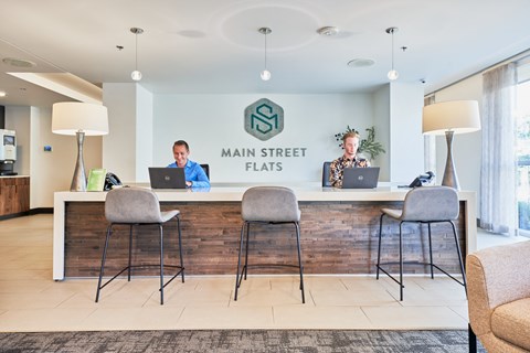 two men sitting at a reception desk with laptops